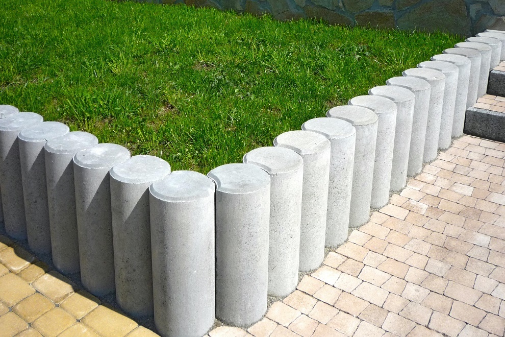 Patch of grass surrounded by gray concrete bollards