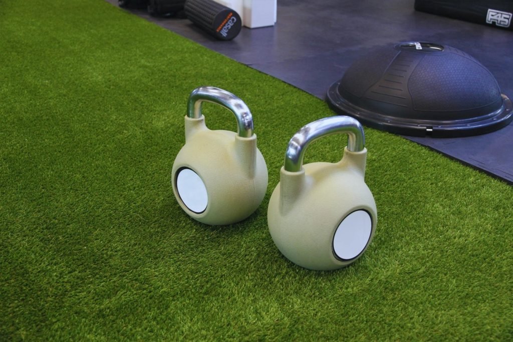 Kettle bells placed on artificial turf in a gym designed for functional training