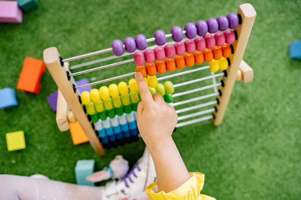 Little hand playing with an abacus standing on artificial turf