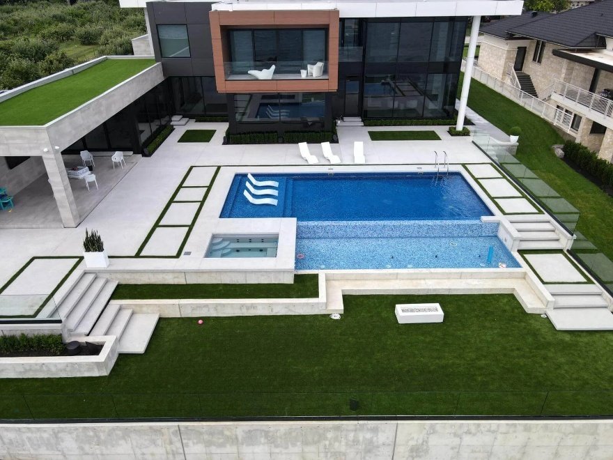 An amazing swimming pool surrounded by synthetic grass in a yard