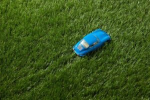 Blue toy car sitting on lush artificial grass