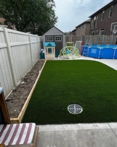 Modern garden with pavement and synthetic turf alongside a white fence