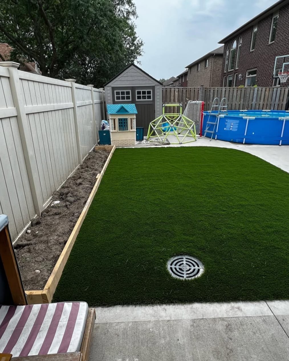Modern garden with pavement and synthetic turf alongside a white fence