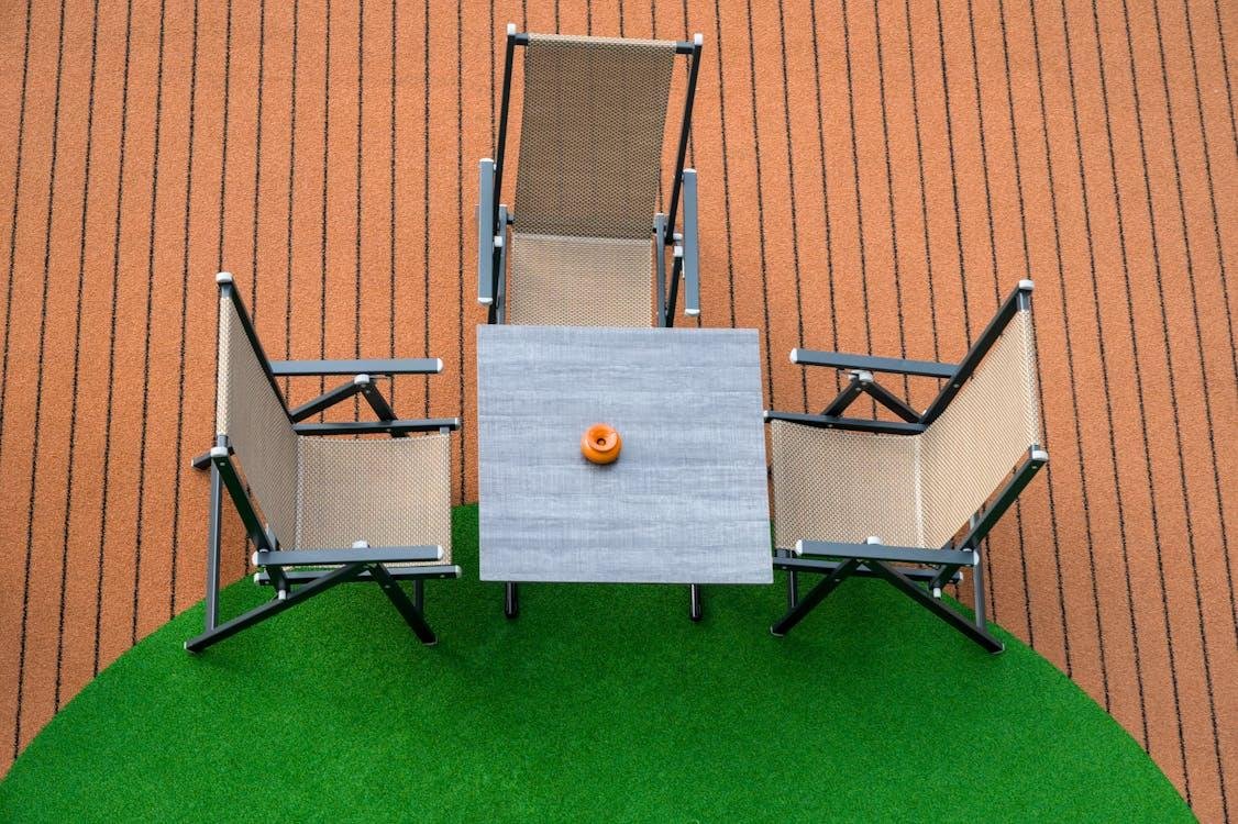 An image of a table and three chairs on fake grass