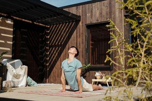 Man practicing yoga in a peaceful backyard wellness area with greenery