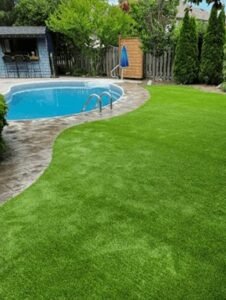 Artificial turf backyard landscape in Essex with patio and fire pit design features