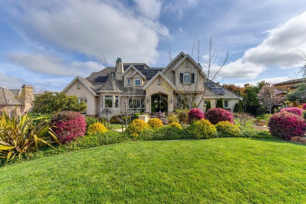 a house with different types of plants and flowers in the front yard
