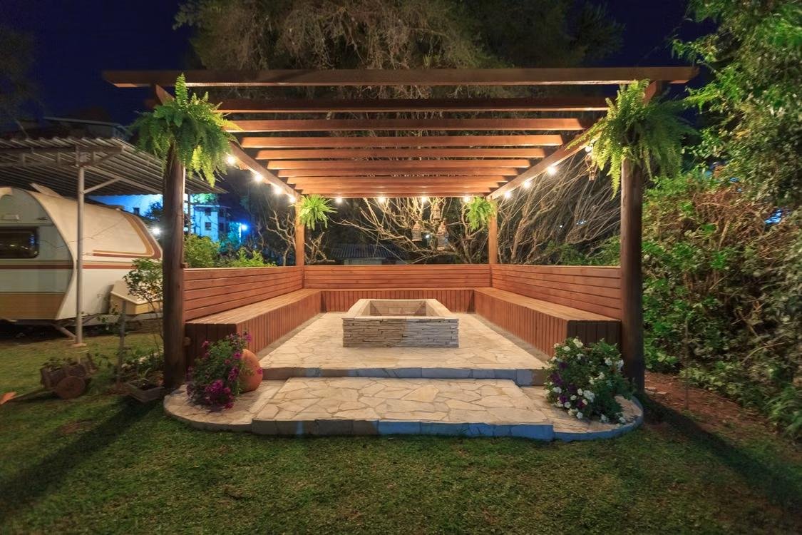 a wooden gazebo outside in a backyard surrounded by greenery and lights