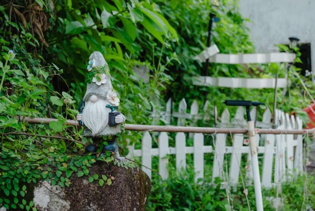 a garden with lush greenery, gnomes, and fences
